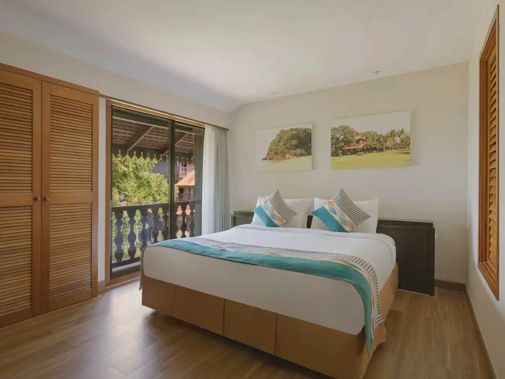 Traditional wooden-style Superior Room bedroom looking out toward the South China Sea coastline at Club Med Cherating resort